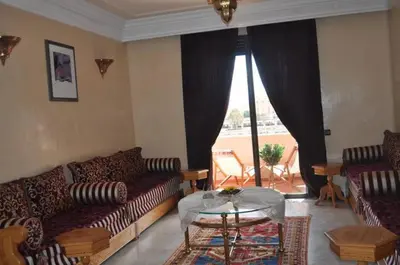 a living room with couches and a table and a window at Appartement Elias Marrakech in Marrakech