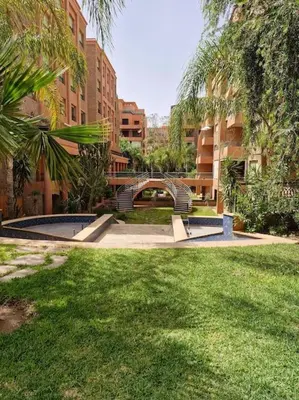 a park with chairs and a bridge in the grass at Marrakech appartement babylon2 in Marrakech