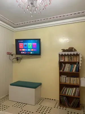 a tv mounted on a wall next to a book shelf at The Red Flat in Marrakech