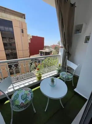 a balcony with two tables and chairs on a balcony at Guéliz appartemment Piscine à la résidence in Marrakech