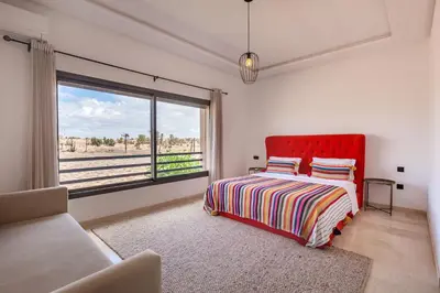 a bedroom with a red bed and a large window at Villa Gina, chic et Moderne avec piscine&terrasse in Marrakech
