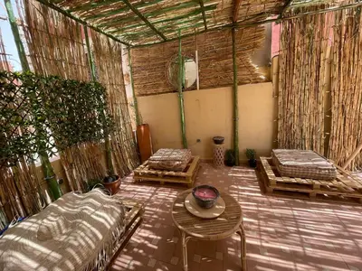 an outdoor room with two beds and a table at Les Nuits de Miel - Marrakech in Marrakech