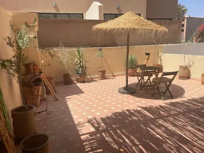 a patio with a table and an umbrella and plants at Les Nuits de Miel - Marrakech in Marrakech