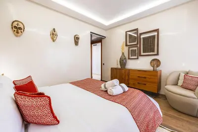 a bedroom with a white bed and a chair at Luxury 2-Bedroom Apartment in Hivernage Pool Residence Near Casino in Marrakech