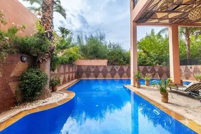 a swimming pool with blue water in a backyard at Luxury 2-Bedroom Apartment in Hivernage Pool Residence Near Casino in Marrakech
