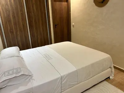 a white bed in a room with a wooden door at Burj Malak appartement dans une résidence privée avec piscine in Marrakech