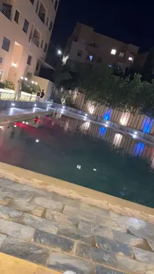 a pool of water at night with buildings at Burj Malak appartement dans une résidence privée avec piscine in Marrakech