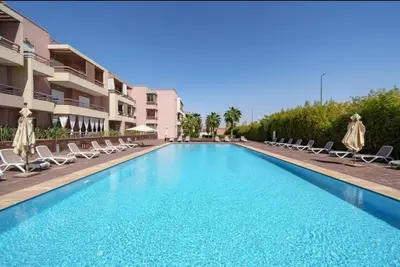 a large swimming pool with chairs and umbrellas at Luxury Apartment in Marrakech in Marrakech