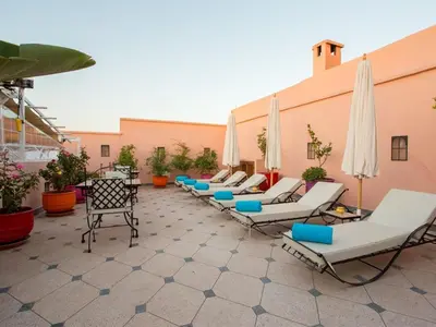 a row of lounge chairs and umbrellas on a patio at Riad Magda & Spa in Marrakech