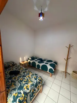 a bedroom with two beds and a cross on the wall at Riad Kinane Romann in Marrakech