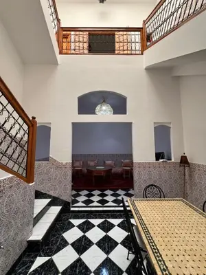 a lobby with a table and chairs and a checkerboard floor at Riad Kinane Romann in Marrakech