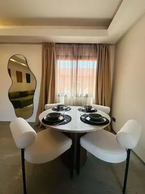 a dining room table with white chairs and a mirror at Luxueux 1 Chambre Guéliz Centre in Marrakech