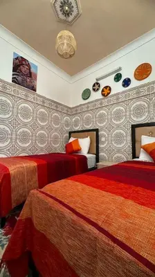 a bedroom with two beds and a clock on the wall at Central Marrakesh Medina Apartment in Marrakech