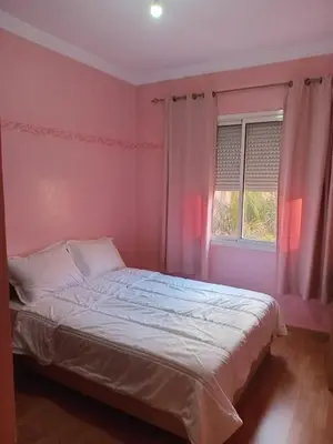 a bedroom with a bed with pink walls and a window at Superbe Appartement 2 chambres à AL FADL Marrakech in Marrakech