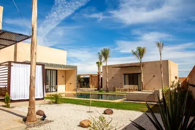 a house with a swimming pool and palm trees at Villa Chafti in Douar Khalifa Ben Mbarek