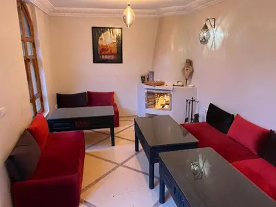 a living room with red couches and a fireplace at Riad Chameleon in Marrakech