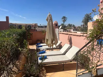 three lounge chairs and an umbrella on a balcony at Riad Chameleon in Marrakech
