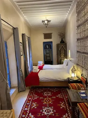 a bedroom with a large bed and a red rug at Riad Chameleon in Marrakech
