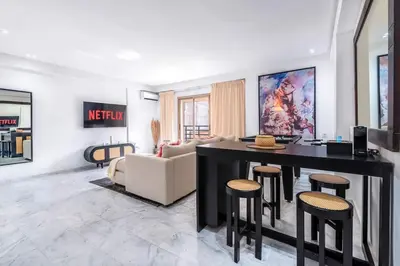 a living room with a couch and a table and stools at Fun-filled luxury city center apartment in Marrakech