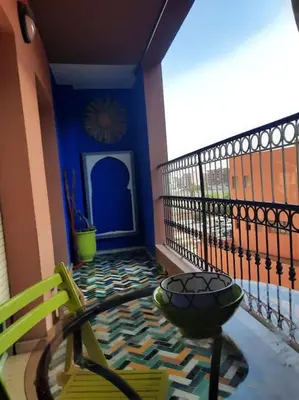 a balcony with a table and a blue wall at Top Appartement 1 Rue Yves Saint Laurent for 1-2 Per- Touristes International in Marrakech