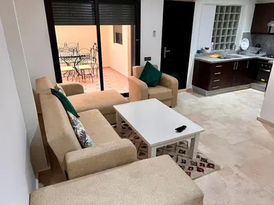 a living room with chairs and a table and a kitchen at Résidence Miramas 2 E1 in Marrakech