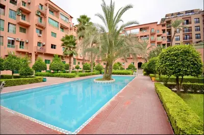 a swimming pool in a resort with palm trees and buildings at Charming Two-Bedroom Apartment in Gueliz,Marrakesh in Marrakech