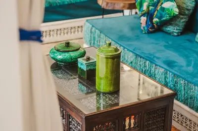 two green candles on a glass table next to a bed at RIAD Dar Argana 100m Place Jemaa el- Fna heated Pool in Marrakech