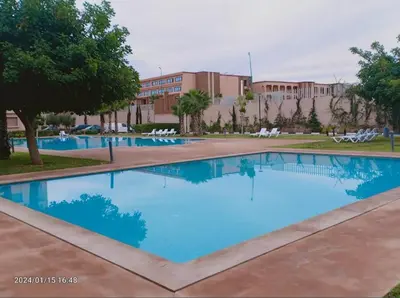 a large pool with blue water in front of a building at Appartement au coeur de Marrakech avec deux piscines et une charmante vue in Marrakech