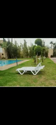 a white object laying on the grass near a pool at Appartement au coeur de Marrakech avec deux piscines et une charmante vue in Marrakech