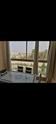 a table and chairs in a room with a window at Appartement au coeur de Marrakech avec deux piscines et une charmante vue in Marrakech