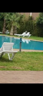 a white chair sitting next to a swimming pool at Appartement au coeur de Marrakech avec deux piscines et une charmante vue in Marrakech