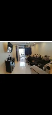 a living room with a couch and a tv at Appartement au coeur de Marrakech avec deux piscines et une charmante vue in Marrakech