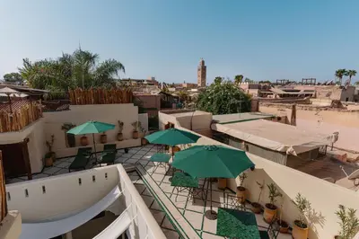 an outdoor patio with green umbrellas and chairs at Riad Senja in Marrakech