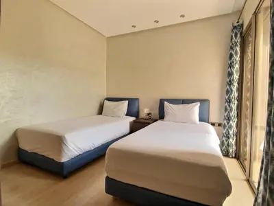 two beds in a small room with a window at Jade Prestigia Golf in Marrakech