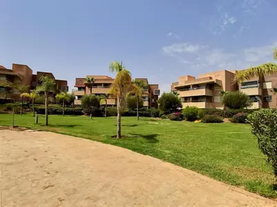 a park with palm trees in front of a building at Jade Prestigia Golf in Marrakech