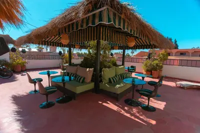 a patio with tables and chairs and a thatch umbrella at Riad Tawja in Marrakech