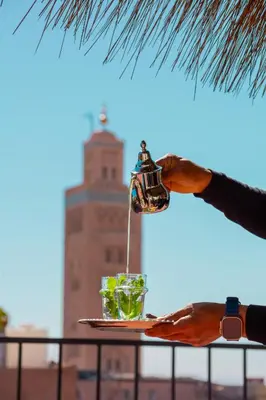 a person is holding a drink on a tray with a drink pitcher at Riad Tawja in Marrakech