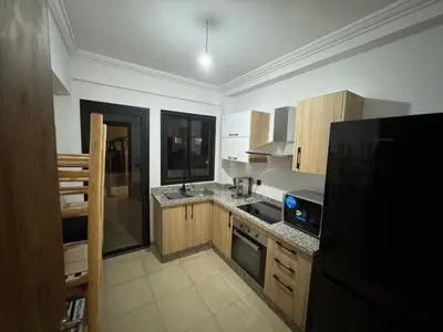 a kitchen with wooden cabinets and a black refrigerator at Luxury Apartment Hivernage Marrakech in Marrakech