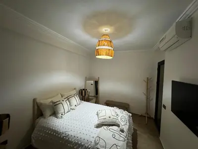 a bedroom with a white bed with pillows and a lamp at Luxury Apartment Hivernage Marrakech in Marrakech