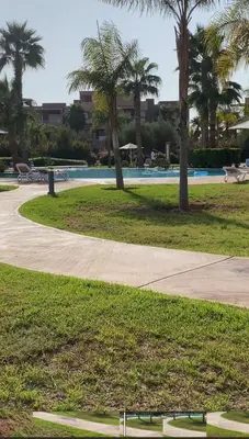 a park with a swimming pool and palm trees at Prestigia marrakech in Marrakech