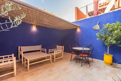 a patio with a table and chairs and a blue wall at Appartement avec terrasse et piscine in Marrakech