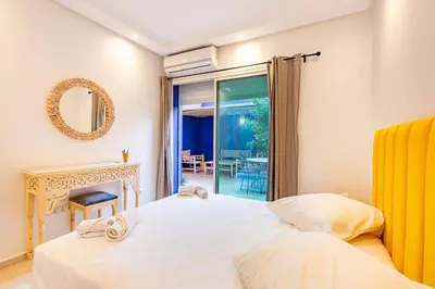 a bedroom with a bed with a mirror and a window at Appartement avec terrasse et piscine in Marrakech