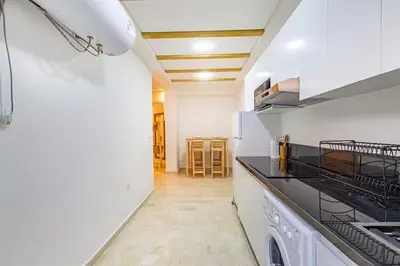 a kitchen with white cabinets and a stove top oven at Appartement avec terrasse et piscine in Marrakech