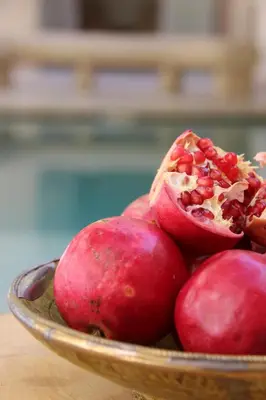 a bowl of red pomegranates on a table at Riad Emberiza Sahari in Marrakech