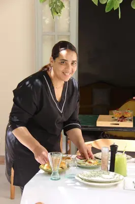 a woman standing at a table preparing food at Riad Emberiza Sahari in Marrakech