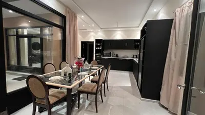 a dining room with a table and chairs and a kitchen at Ourika immoblier in Marrakech