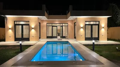a swimming pool in front of a house at night at Ourika immoblier in Marrakech