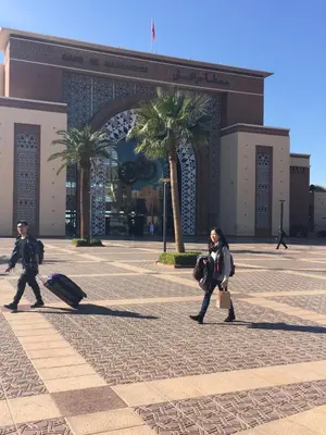 a woman walking in front of a building with luggage at Zina in Marrakech
