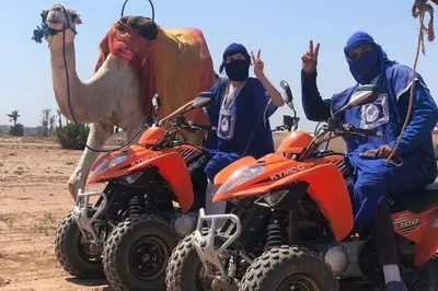 three people on atvs and a camel in the desert at quad marrakech in Dar Caïd Layadi