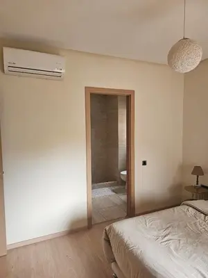 a bedroom with a bed and a bathroom with a toilet at Bel appartement avec piscine et jardin in Marrakech